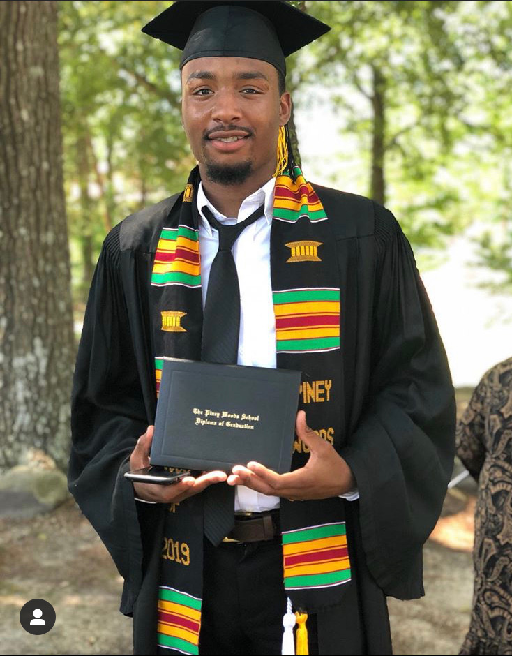 Graduate in cap and gown holding a diploma cover