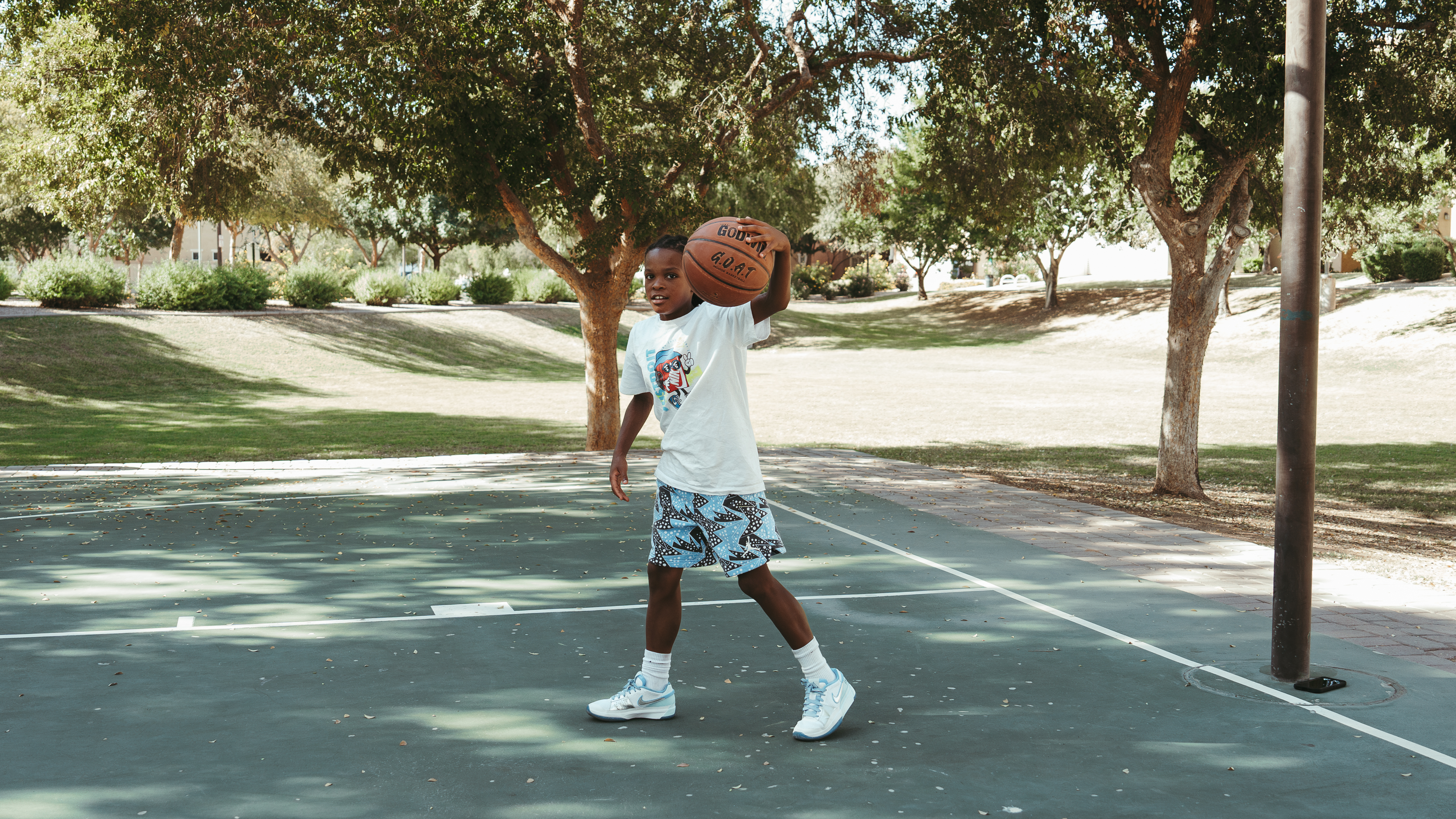 Child holding a basketball on an outdoor court